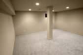 finished basement room with support column and carpeted floor.