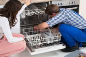 man and woman looking inside an open dishwasher
