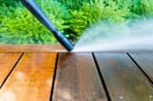 pressure washer cleaning dirt off a wooden patio