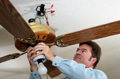 man working on a ceiling fan fixture