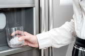 woman getting ice from ice maker in refrigerator