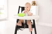 A baby in a wooden high chair.