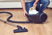 A woman empties a vacuum.