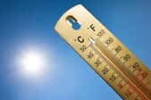 A thermometer with the sun in the background.