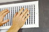 hands checking drafts from heating vents