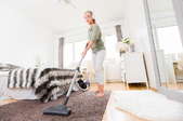 A woman vacuums a bedroom.