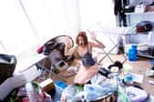 An overwhelmed young woman sits surrounded by a mess.