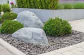 large rocks in gravel bed with bushes