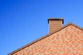A home roof with a brick chimney extending above it.