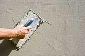 Using a trowel to spread stucco on a wall.