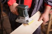 man using a sander to sand the edge of a board