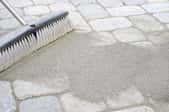 brush moving paver sand into walkway