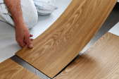hands installing laminate floor panel
