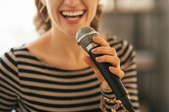 A close-up of a woman singing karaoke into a microphone.