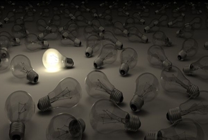 A grouping of light bulbs with one lit.