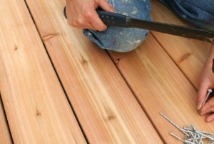 a person nailing new wooden planks onto a deck