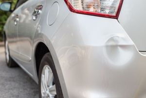 a silver car with a dent
