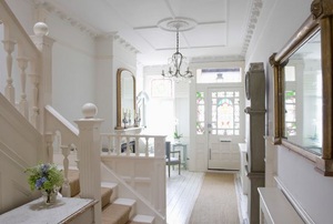 A white foyer with a staircase and mirror.