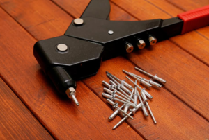 a rivet gun with rivets laying next to it