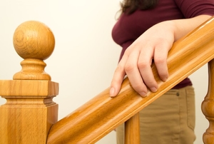 A woman holds a wood railing.