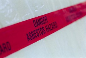 A red tape sign warning against asbestos danger.