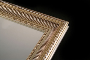 A close picture of a mirror with an elegant frame.