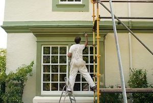 A professional painter working on a home exterior.