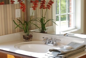 A bathroom prepped for guests with fresh hand towels and flowers.