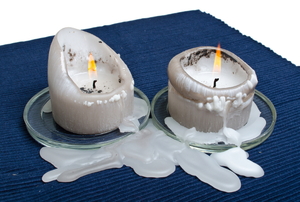 A pair of candles dripping wax on a table cloth.