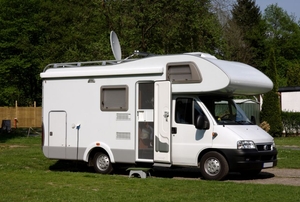 White RV parked with door open and dish on top