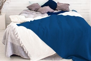 a bed piled up with grey and blue pillows and a blue comforter
