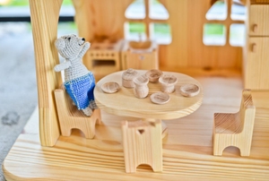 A wooden dollhouse with a tiny table