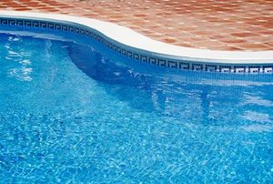 A close-up of a clean, in ground pool during the summer.