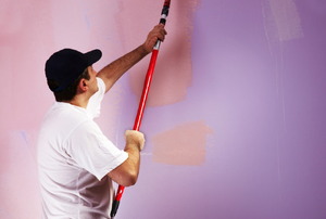 A man painting a room two shades of purple.