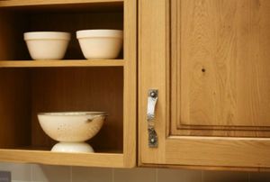 a kitchen cabinet with dishes on a shelf next to it