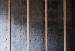 A series of four wall studs with a cement wall in the background.