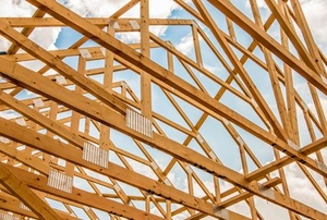 Wooden roof framing against a cloudy sky