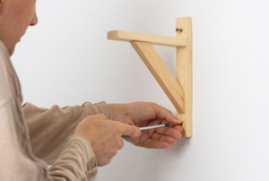 person installing wall mount for shelf