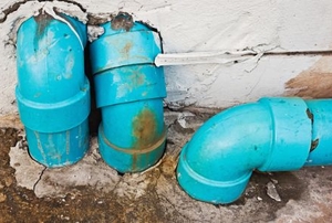 Old, blue PVC pipe with rust stains and damage on the surface.