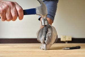 A hammer and nail set punching a nail into a wood floor.