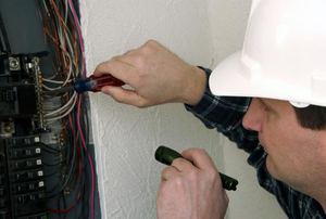A man inspects a circuit breaker panel.
