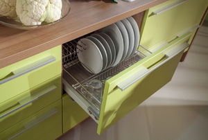 A modern kitchen with a drawer open and plates inside. 
