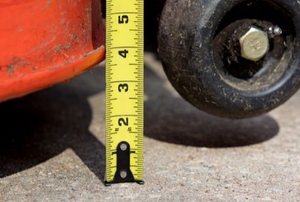 lawn mower lifted off concrete next to tape measure