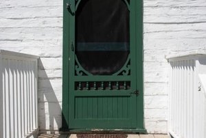 green wooden screen door with fancy carving