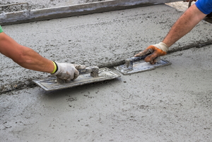 Trowels smoothing and leveling the surface of wet concrete.