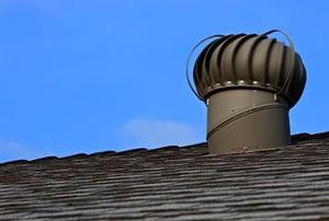 A turbine vent on a roof against a blue sky.