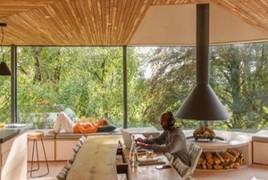 man in room with wood ceilings and large windows