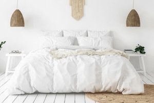 clean, elegant bedroom with grass rug and lamps, large white bed, white floor and white walls