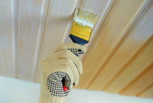 a paintbrush applying paint to a tongue and groove ceiling