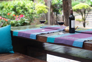 backyard patio with dark wooden table, wine glasses and bottle, and blue and purple fabrics